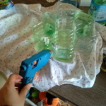 Occorrente: bottiglie di plastica, stoffa, colla a caldo, forbici.